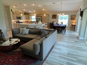 A modern living room with a sectional sofa, a coffee table, and a dining area with a table and chairs.