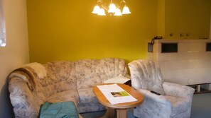 Ein Wohnzimmer mit einer Couch, einem Sessel und einem kleinen Tisch mit Papieren.