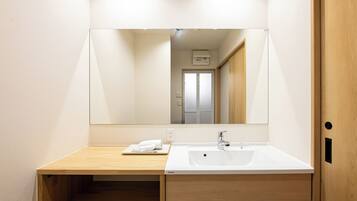 A modern bathroom with a wooden vanity, a white sink, and a large mirror.