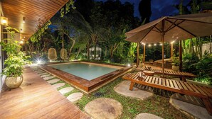 A pool area with wooden decking, stone steps, and lounge chairs under a canopy. - Hutan Villa - Open Bath and Private Pool (Ubud)