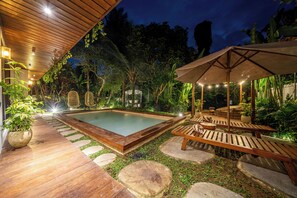 A pool area with wooden decking, stone steps, and lounge chairs under a canopy. - Hutan Villa - Open Bath and Private Pool (Ubud)