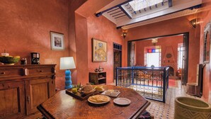 A traditional Moroccan interior with a wooden table set with food, a coffee machine, and a decorative lamp. - Elegant Refuge in Medina with Ocean View (Essaouira)