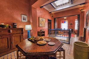 A traditional Moroccan interior with a wooden table set with food, a coffee machine, and a decorative lamp. - Elegant Refuge in Medina with Ocean View (Essaouira)