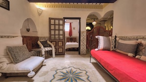 A traditional Moroccan room with a bed, sofa, and a decorative floor pattern. - Elegant Refuge in Medina with Ocean View (Essaouira)