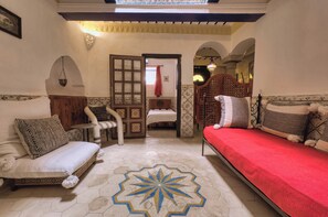 A traditional Moroccan room with a bed, sofa, and a decorative floor pattern. - Elegant Refuge in Medina with Ocean View (Essaouira)