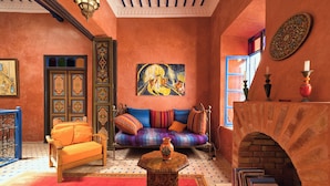 A Moroccan-style room with a sofa, a small table, a fireplace, and a painting on the wall. - Elegant Refuge in Medina with Ocean View (Essaouira)