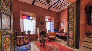 A traditional interior with a patterned rug, a sofa, a bed with colorful bedding, and a fireplace. - Elegant Refuge in Medina with Ocean View (Essaouira)