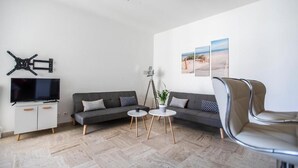 Ein modernes Wohnzimmer mit einer Couch, zwei runden Tischen, einem Fernseher und einem Deckenventilator.