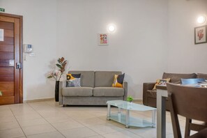 Ein Wohnzimmer mit einer Couch, einem Glastisch und einem braunen Sessel.