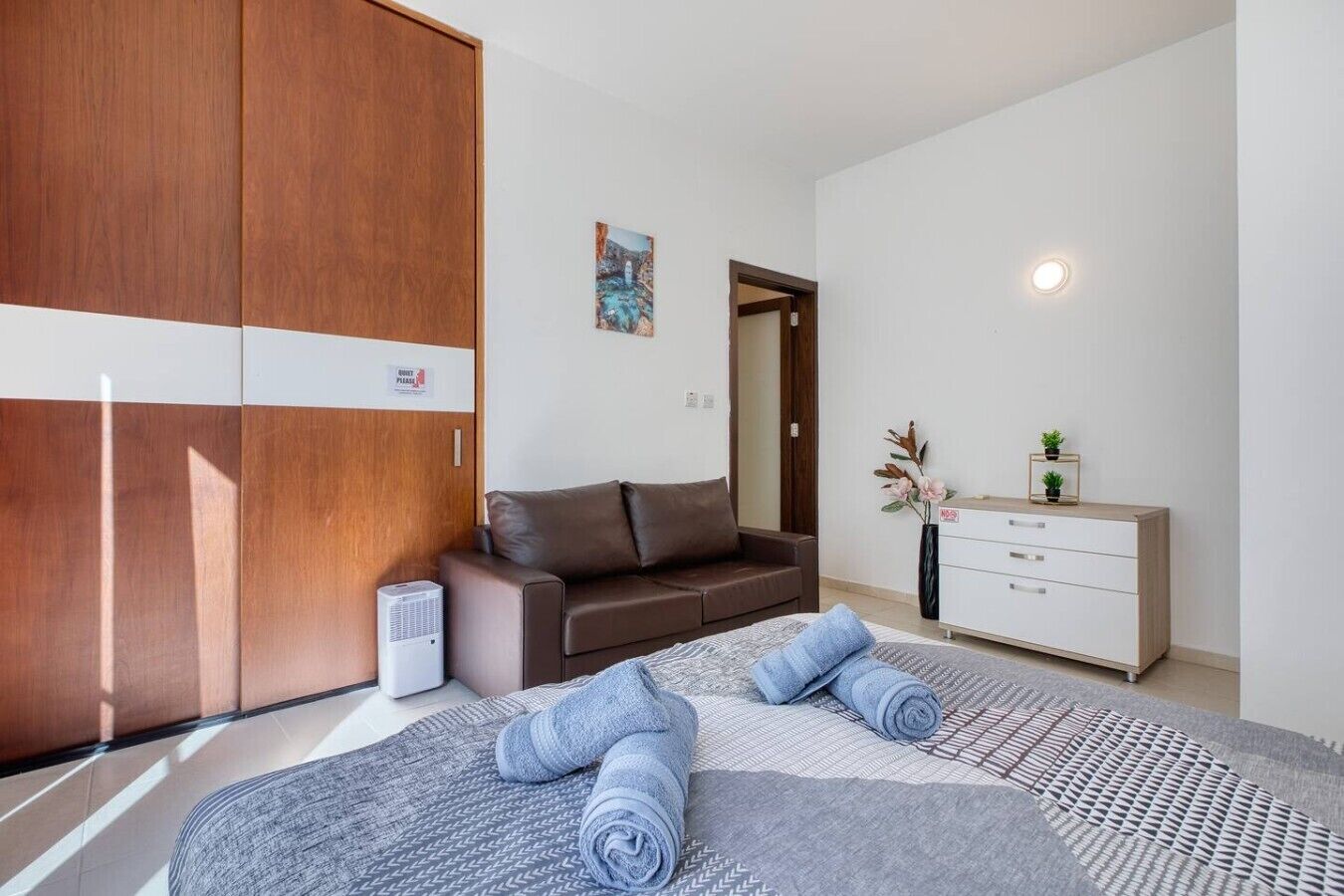 A modern bedroom with a bed, a sofa, a dresser, and a wardrobe.