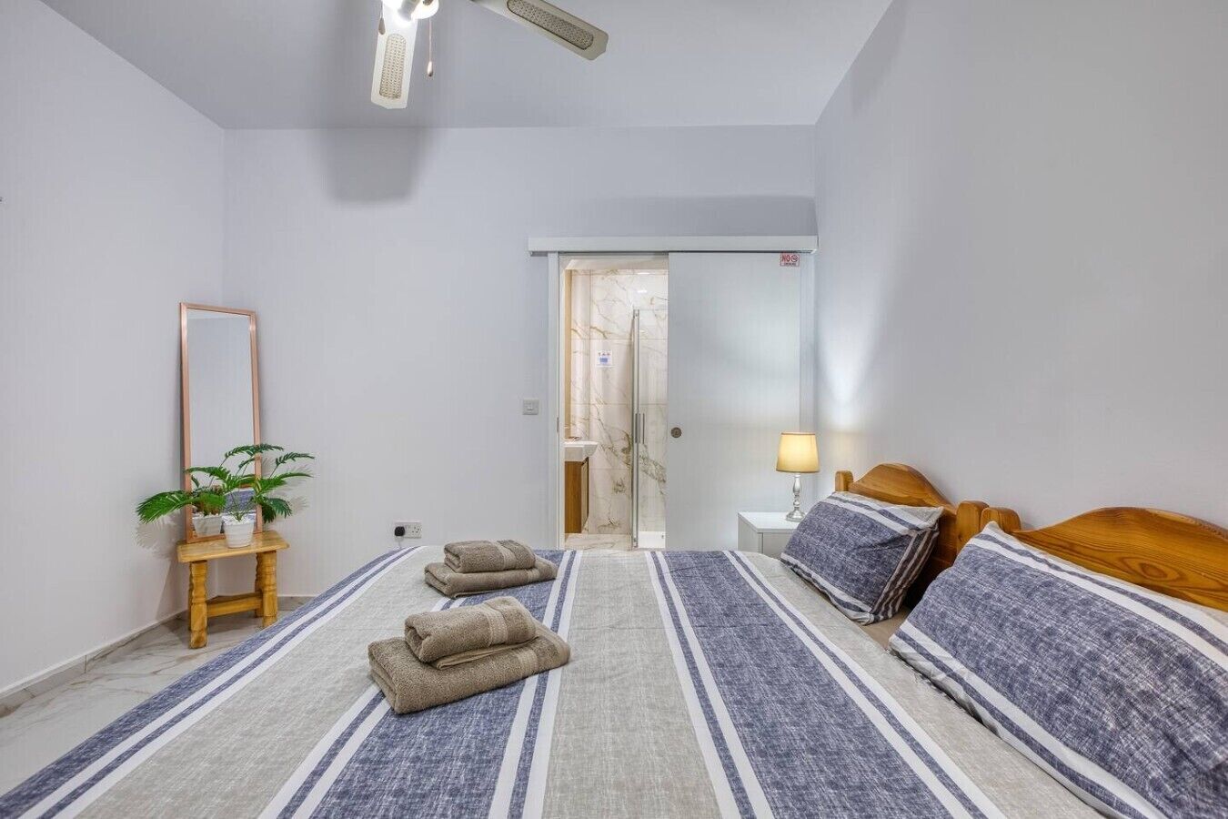 Habitació d'hotel amb llit, taula de nit, làmpada i mirall.