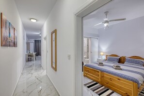 Ein Schlafzimmer mit einem Bett, einem Deckenventilator, einem Nachttisch und einem durch eine offene Tür einsehbarer Badezimmer.