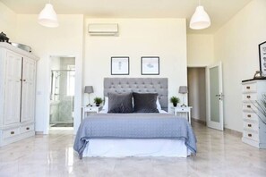 A bedroom with a large bed, two bedside tables, a wardrobe, and a door leading to another room. - Luxury Maltese Penthouse with Breathtaking views (Il-Mellieħa)