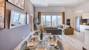 A modern apartment with a dining area, kitchen, and living space with large windows. - Balluta Harbour View (St Julian`s)