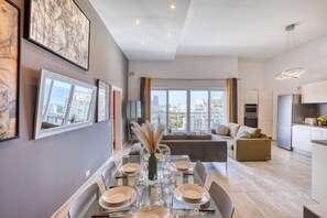 Ein modernes Apartment mit Essbereich, Küche und Wohnbereich mit großen Fenstern.