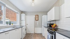 Une cuisine équipée d’un évier, d’un lave-linge, d’une cuisinière et de placards.