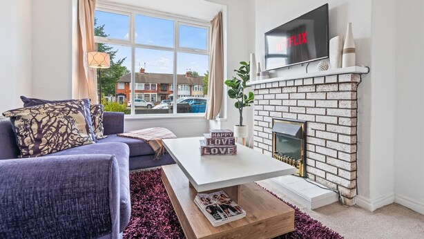Un salon comprenant un canapé, une table basse, une cheminée et un téléviseur fixé au mur.