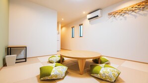 A room with tatami flooring, a round wooden table, and green and white cushions. - Irodori Hotel KAZE (fukuokashi,hakataku,toukou)