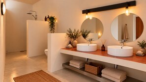 A modern bathroom with two round white sinks, a large mirror, and a shower area. - Coco Canel (Mbour)