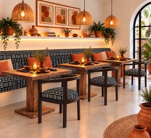 A dining area with wooden tables and chairs, pendant lights, and potted plants. - Coco Canel (Mbour)