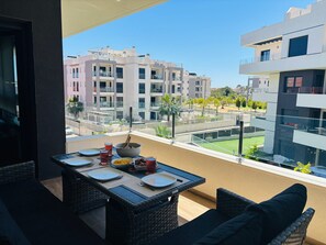 Ein Balkon mit Esstisch für zwei Personen, mit Blick auf eine Wohngegend mit modernen Gebäuden.
