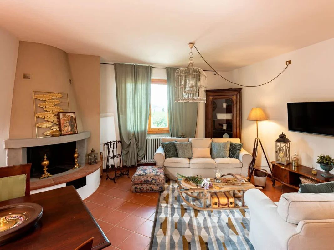 Una sala de estar con chimenea, sofá, mesa de centro y televisor.