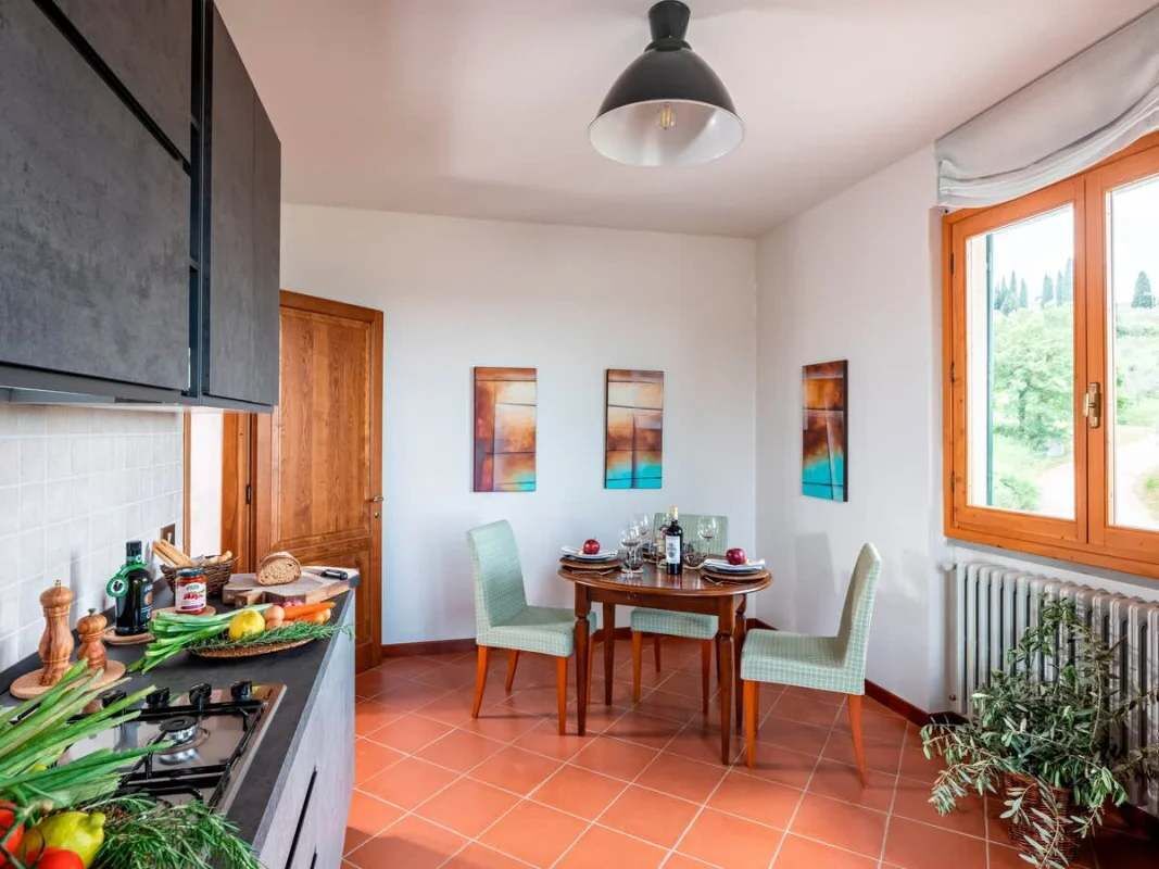 Una cocina con comedor, estufa y ventana con vista a zonas verdes.