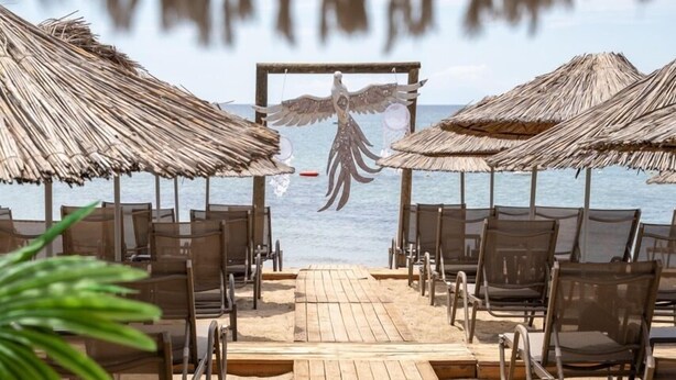 A wooden deck with chairs and thatched umbrellas, leading to a beach. - one lıfe otel (Ayvalık)
