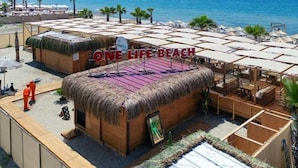 A beachside resort with thatched-roof structures, sun loungers, and a clear view of the sea. - one lıfe otel (Ayvalık)
