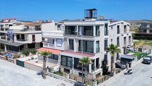 A multi-story residential building with balconies, a rooftop terrace, and a parking area. - one lıfe otel (Ayvalık)