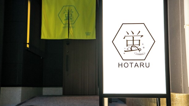 Un cartel enmarcado con un icono de grifo y la palabra 'HOTARU' en forma hexagonal.