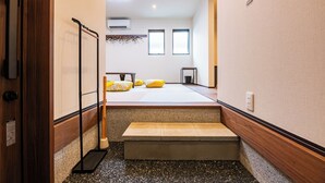 Una habitación de hotel con una cama, un banco, un perchero y una mesita.