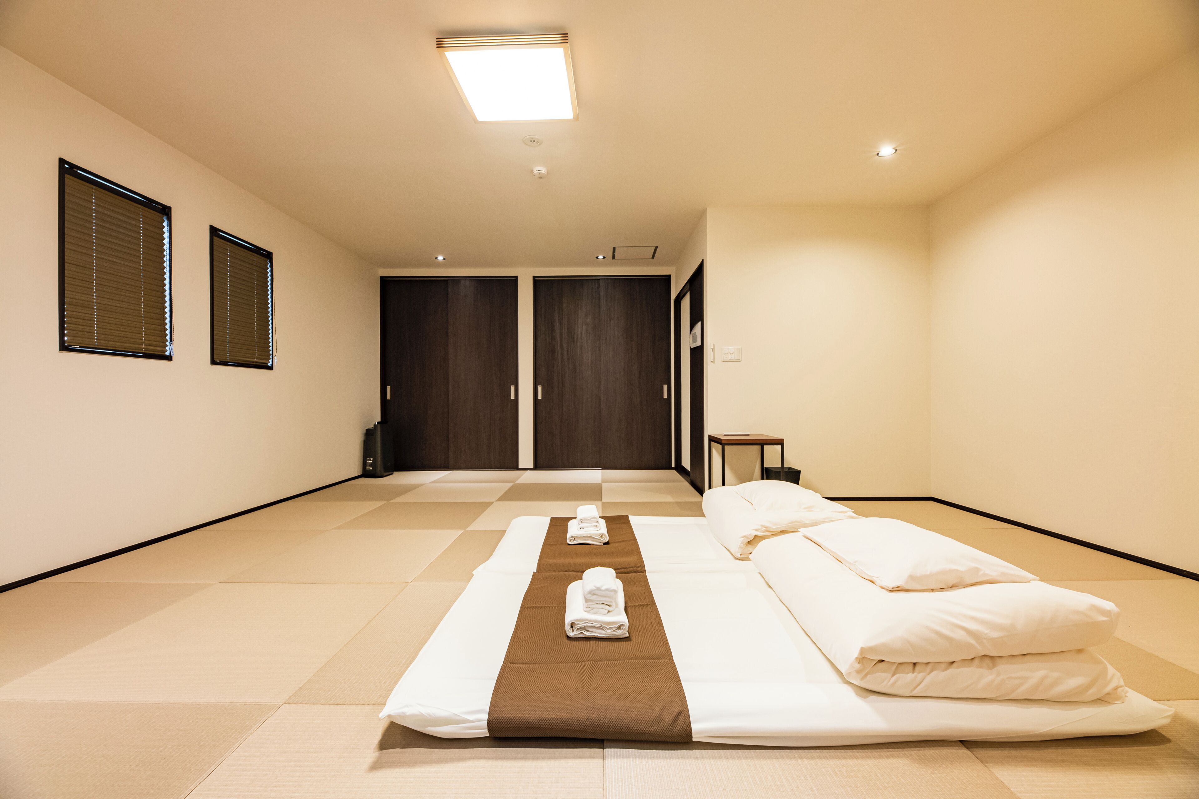 A hotel room with a bed, a small table, and a wardrobe.