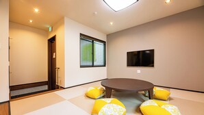 Una habitación con esteras de tatami, una mesa redonda y cojines amarillos.