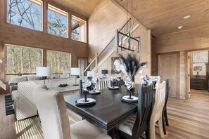 Ein großzügiger Wohnbereich mit einem dunklen Holzesstisch, mehreren Stühlen, einer Couch und einer Treppe, die zu einer oberen Ebene führt.