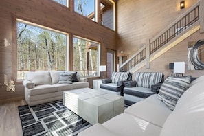 Ein geräumiges Wohnzimmer mit hohen Decken, großen Fenstern und einer Treppe.