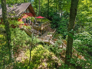 Eine Holzhütte mit einer Veranda und einer Treppe, die zu einer zweiten Ebene führt.