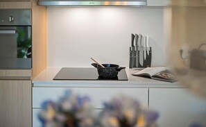 Eine moderne Küche mit Einbauofen, Dunstabzugshaube, einer schwarzen, gefleckten Bratpfanne und einem Messerblock.