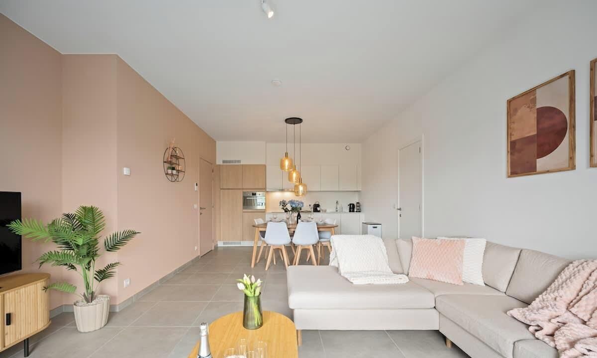 Ein modernes Wohnzimmer mit Sofa, Esstisch und Fernseher.