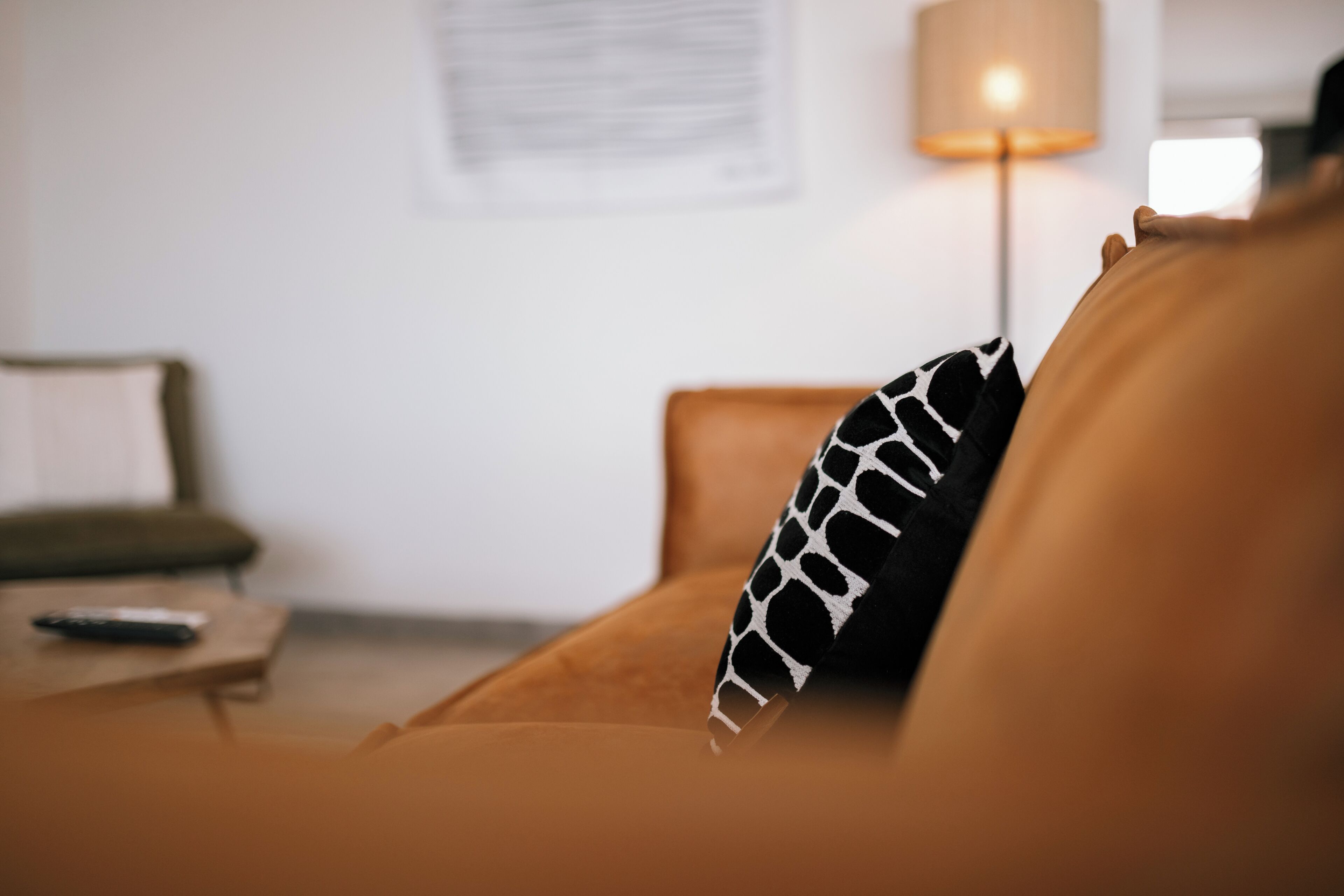 A living room with a sofa, a remote control, and a lamp.