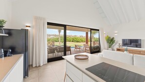 A modern kitchen with a large island, a dining area with outdoor seating, and a TV on the wall. - The Jazmyn - Blue Bay Golf & Beach Resort (Sint Michiel)