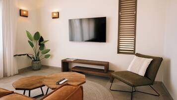 Un salon moderne avec un téléviseur à écran plat, une plante en pot, un canapé, une table basse et un meuble pour la télévision.