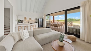 A modern living room with a sofa, a coffee table, and a view of the outdoor patio area. - The Jazmyn - Blue Bay Golf & Beach Resort (Sint Michiel)