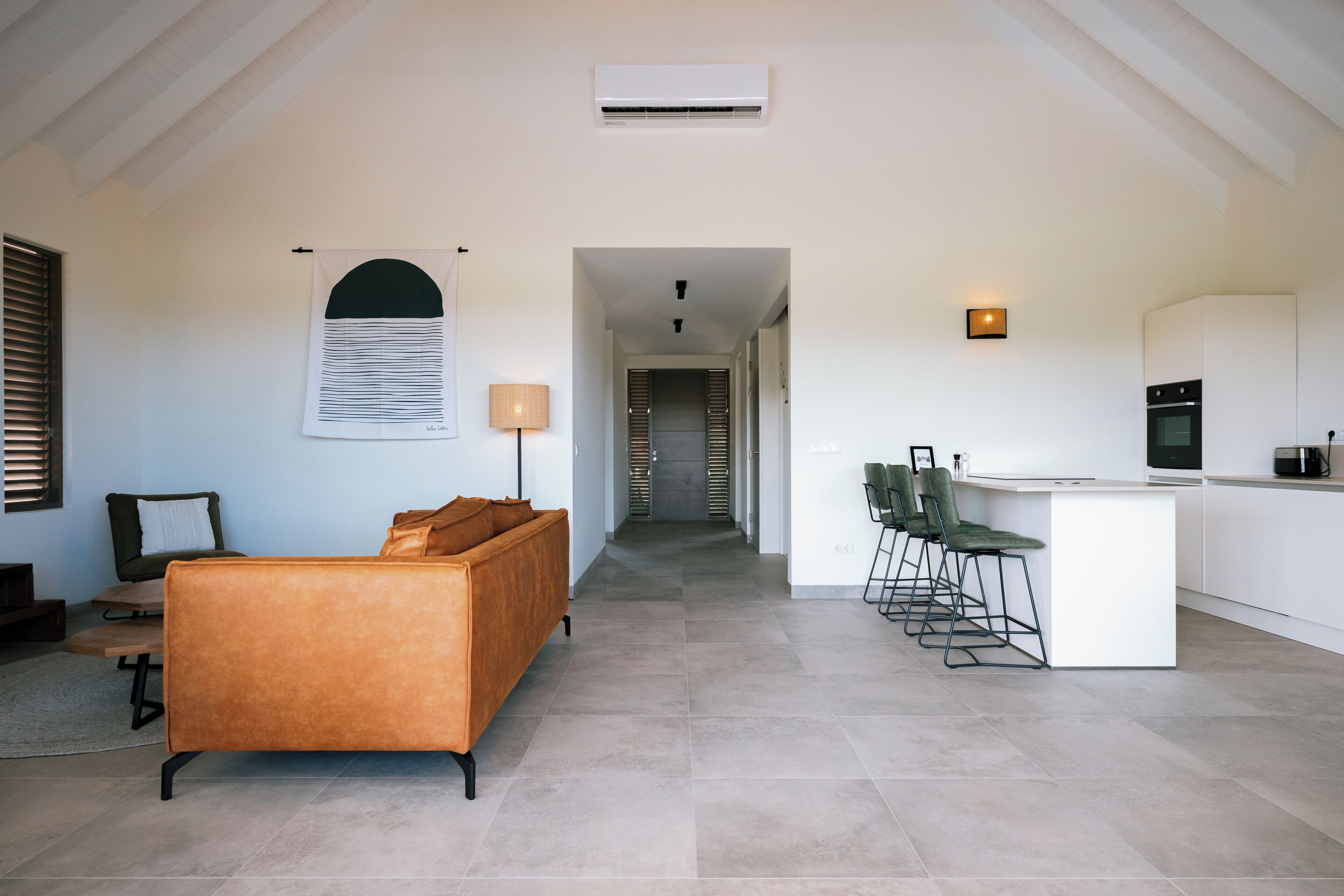 A modern interior with a sofa, a dining area with chairs, a kitchen, and a hallway.
