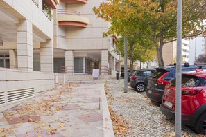 Eine mehrstöckige Parkgarage mit Fliesenboden, geparkten Autos und einem Baum mit Herbstlaub.