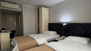 A hotel room with two beds, a desk, and a wardrobe. - BUYAR OTEL  (Samsun)