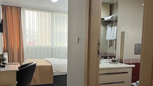 A hotel room with a bed, desk, chair, and a bathroom with a mirror and sink. - BUYAR OTEL  (Samsun)