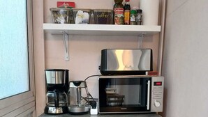 Et tekøkken med kaffemaskine, mikroovn og køleskab.