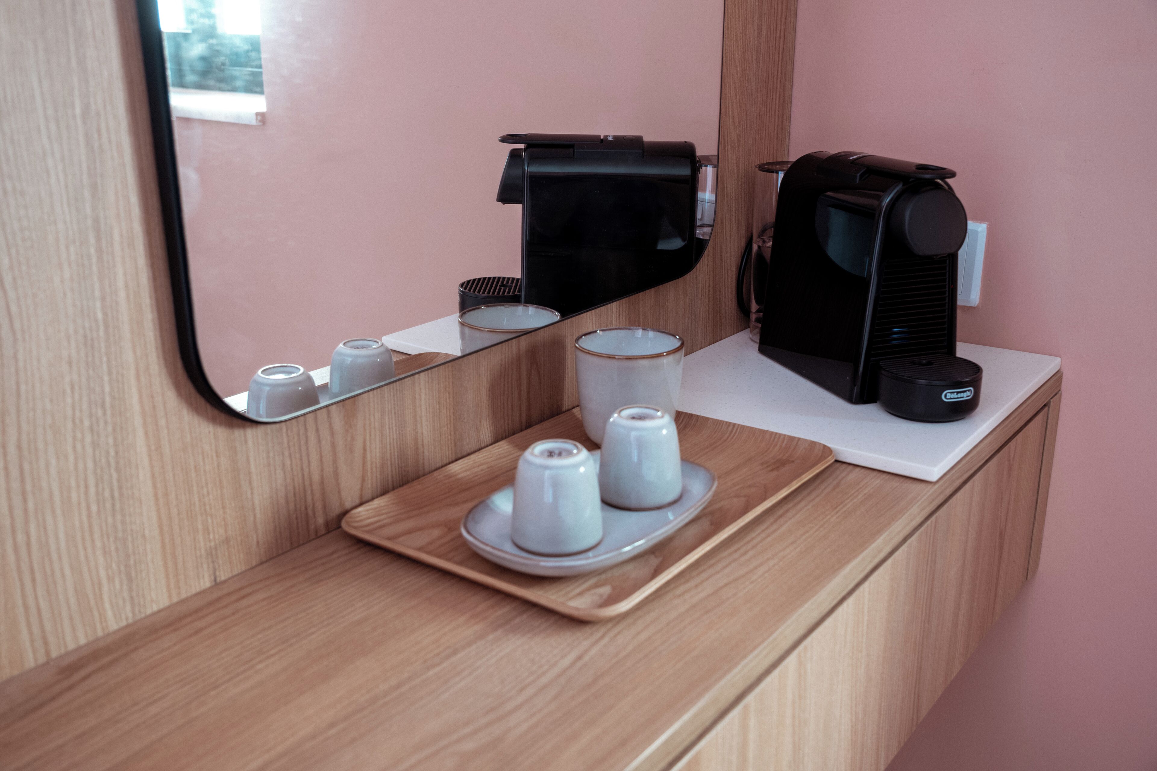 Ein Hotelzimmer mit einem Holznähtisch, einem Spiegel, einer Kaffeemaschine und Salz- und Pfefferstreuern auf einer Ablagefläche.