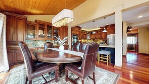 A spacious kitchen with wooden cabinets, a dining table with chairs, and a chandelier. - Private Garage & Laundry, Views of Mammoth Rock, Welcomes Pets (Mammoth Lakes)